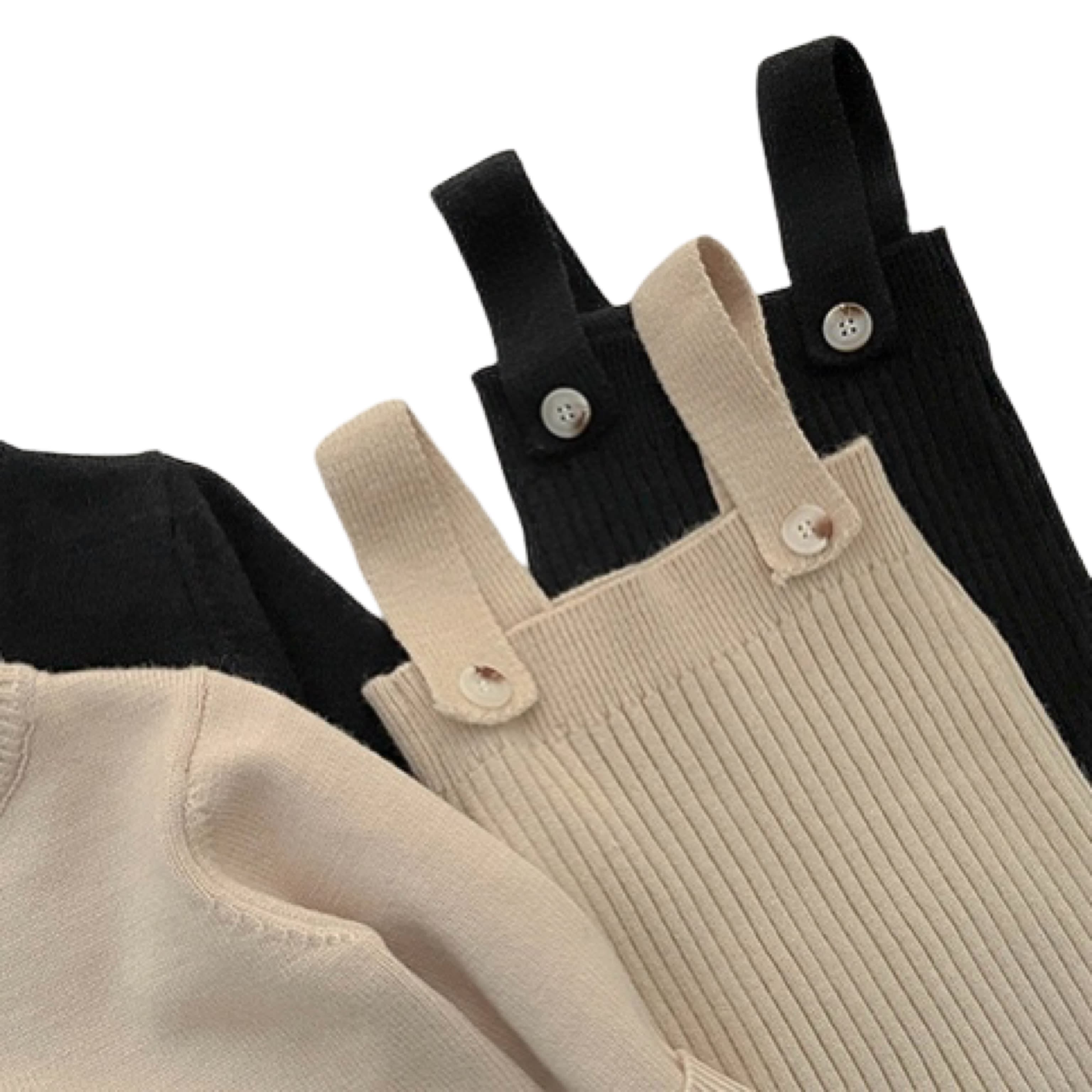 Detail of baby knitted overalls in beige and black showing button straps and ribbed knit texture