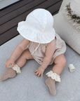 Baby wearing neutral lace frill cotton socks with soft ruffle trim and bow detail