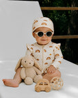 baby girl wearing cream rainbow print long sleeve swimsuit with matching swim hat and sunglasses