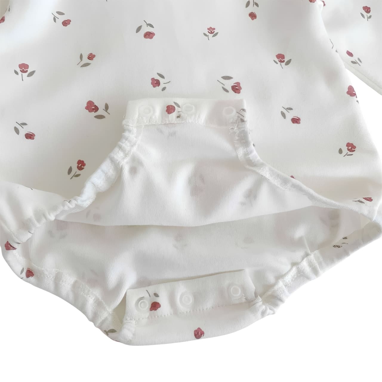 Close-up of baby romper set snap button bottom with soft cotton lining and floral print, easy nappy change design from 4-pack baby outfit