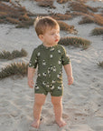 Toddler wearing green sheep print zip swim romper on the beach, soft breathable baby swimwear for summer play