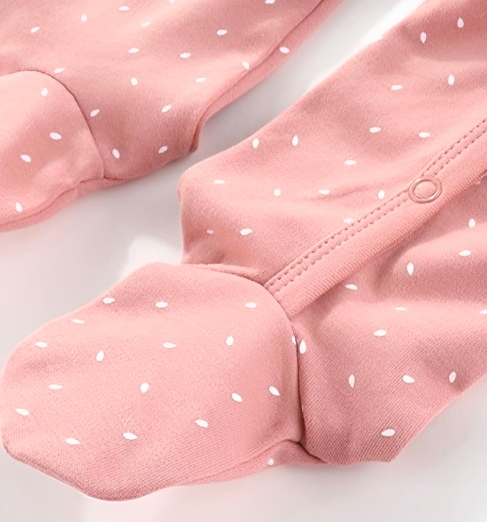Close-up of pink baby cotton sleepsuit with footed design and popper fastening, soft breathable fabric
