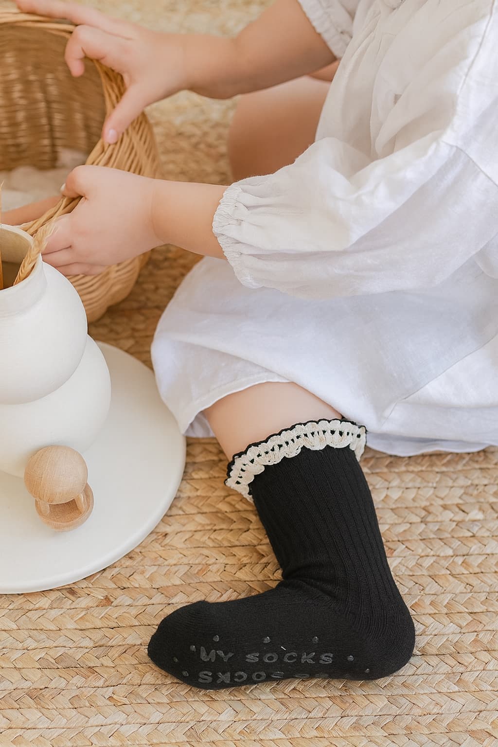 Baby girl wearing black ruffle socks, cozy fit and stylish lace detail