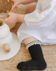 Baby girl wearing black ruffle socks, cozy fit and stylish lace detail