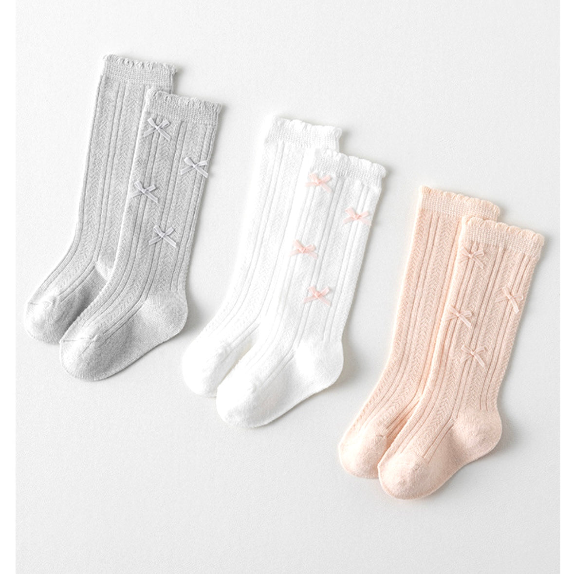Baby wearing white knee-high bow socks – cozy and classic cotton knit BabyWonders UK