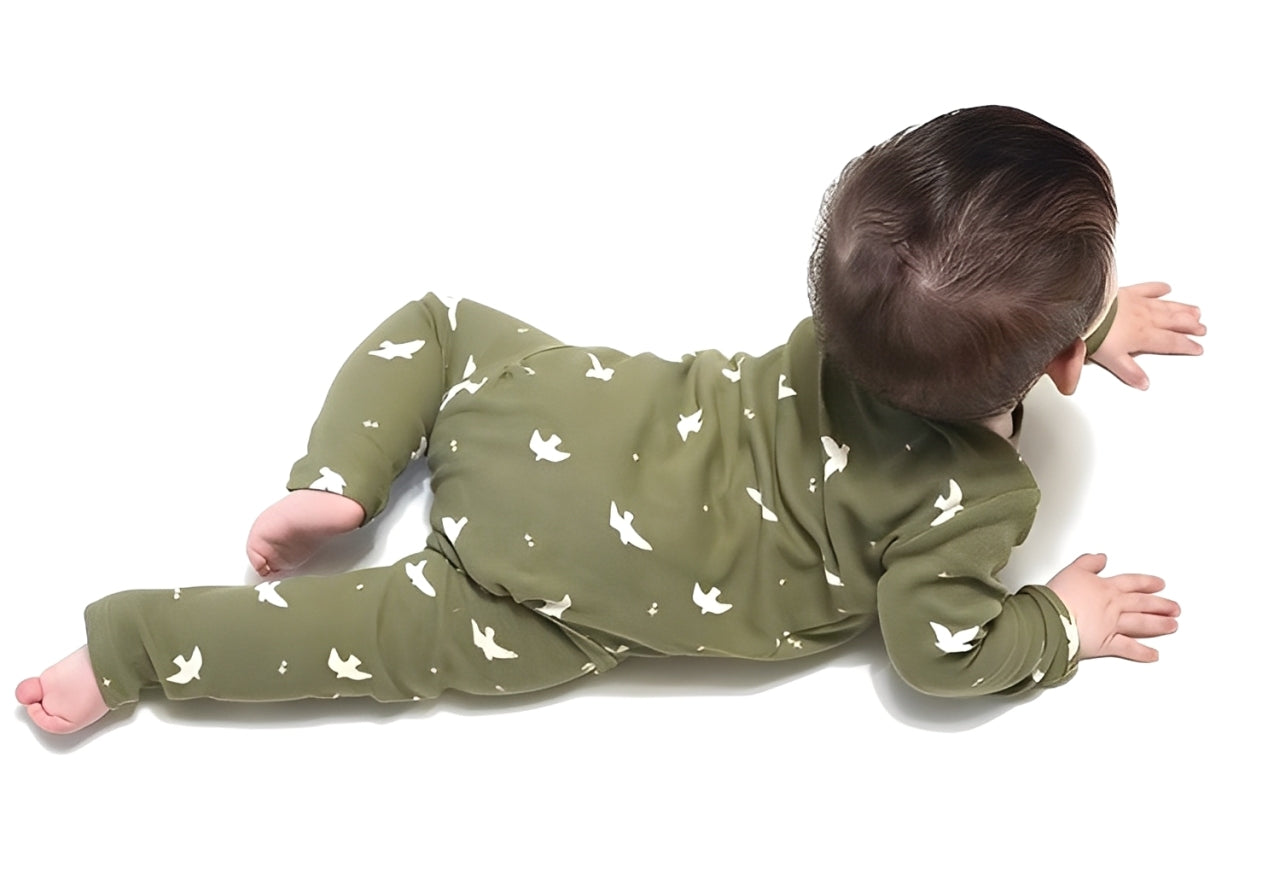 Baby crawling in olive-green cotton romper with white dove print, soft and stretchable fabric for comfort and movement.