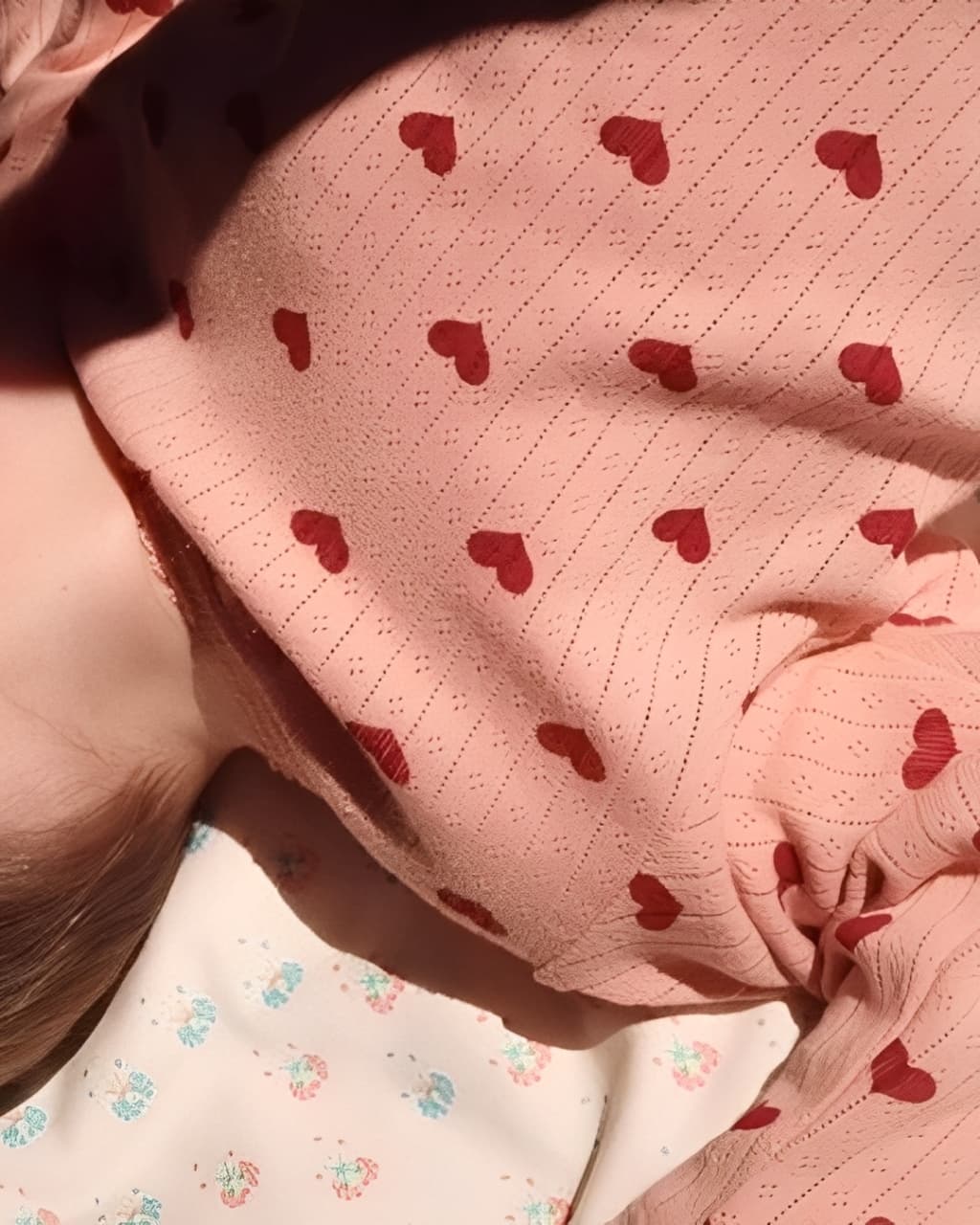 Baby sleeping in pink heart cotton romper, soft ribbed material with comfortable and skin-friendly fit.
