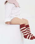 Toddler wearing red and white striped cotton socks, Christmas candy cane inspired design.
