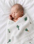 Sleeping newborn baby wrapped in a cactus print cotton blanket with tassel trim, soft breathable baby blanket for everyday comfort.