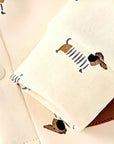 Close-up of sleeve cuff and snap button detail on beige puppy print baby romper.