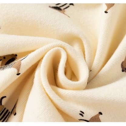 Soft cotton fabric texture with puppy print pattern on beige baby romper.