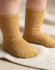Baby wearing mustard cotton socks on feet, soft breathable fabric
