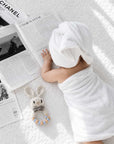 Newborn baby lying on a soft white blanket beside a crochet blue rabbit teether with personalised wooden beads, a thoughtful baby shower gift and newborn essential in the UK.