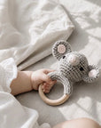 Baby holding a handcrafted crochet elephant wooden ring rattle, ideal for sensory development, teething relief and newborn baby gifts.