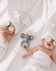 Twin newborn babies relaxing beside a crochet elephant teether with a wooden teething ring and personalised beads, a thoughtful baby shower gift and newborn essential in the UK.