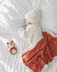 Sleeping newborn baby with crochet fox rattle and coral tassel baby blanket, sensory toy and nursery essential for baby shower gifts.