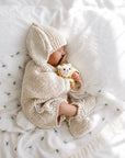 Newborn baby holding a crochet lion rattle in a soft neutral nursery, a thoughtful baby shower gift and newborn essential in the UK.