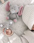 Newborn baby holding a handcrafted crochet elephant rattle beside a matching big-ear elephant comfort toy, a thoughtful baby shower gift and nursery essential.