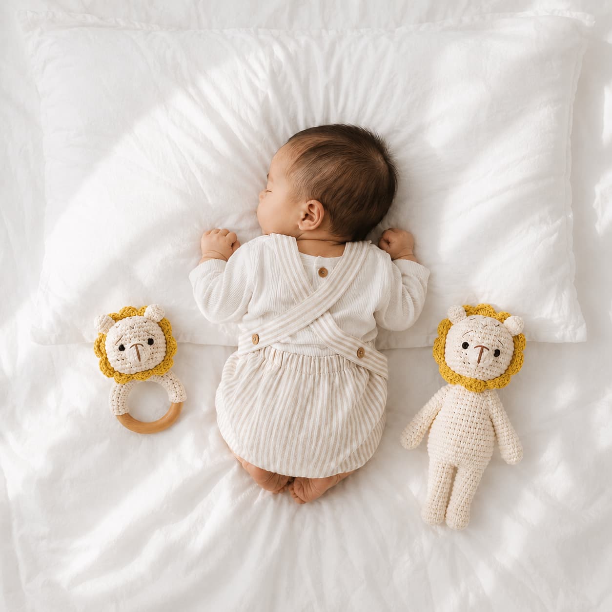 Newborn baby resting beside a handcrafted crochet twin lion rattle set with lion comfort toy and wooden ring rattle, a thoughtful baby shower gift and nursery essential.