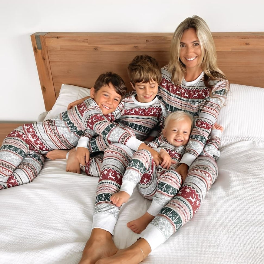 Mom and kids wearing matching Christmas pajamas with festive reindeer and snowflake pattern