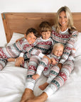 Mom and kids wearing matching Christmas pajamas with festive reindeer and snowflake pattern
