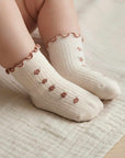Baby wearing cream floral ruffle knit socks with embroidered flowers, soft and breathable cotton

