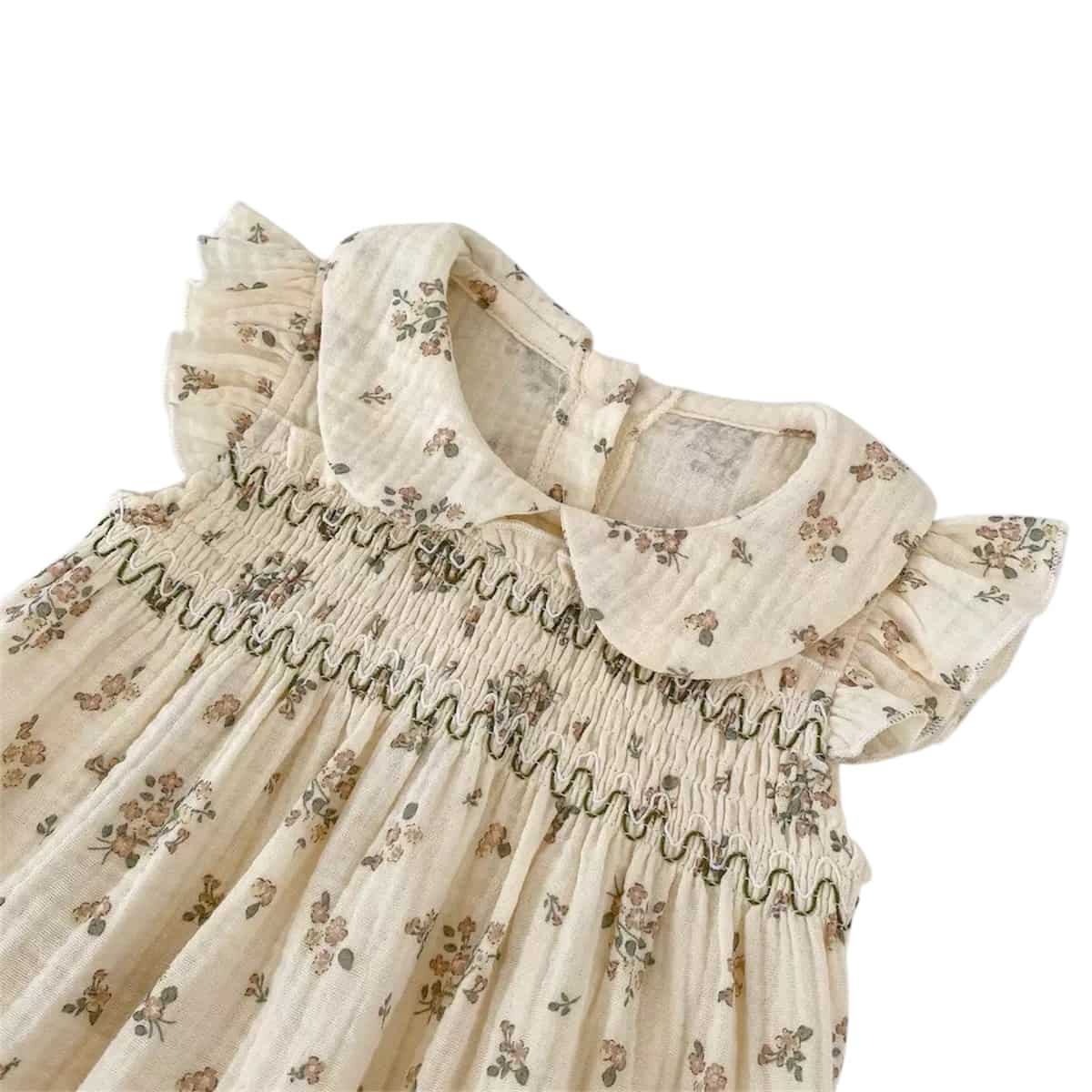 Close-up of floral smocked baby romper with Peter Pan collar and ruffle sleeves, soft breathable cotton fabric for baby summer outfit
