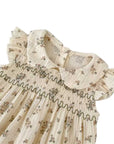 Close-up of floral smocked baby romper with Peter Pan collar and ruffle sleeves, soft breathable cotton fabric for baby summer outfit

