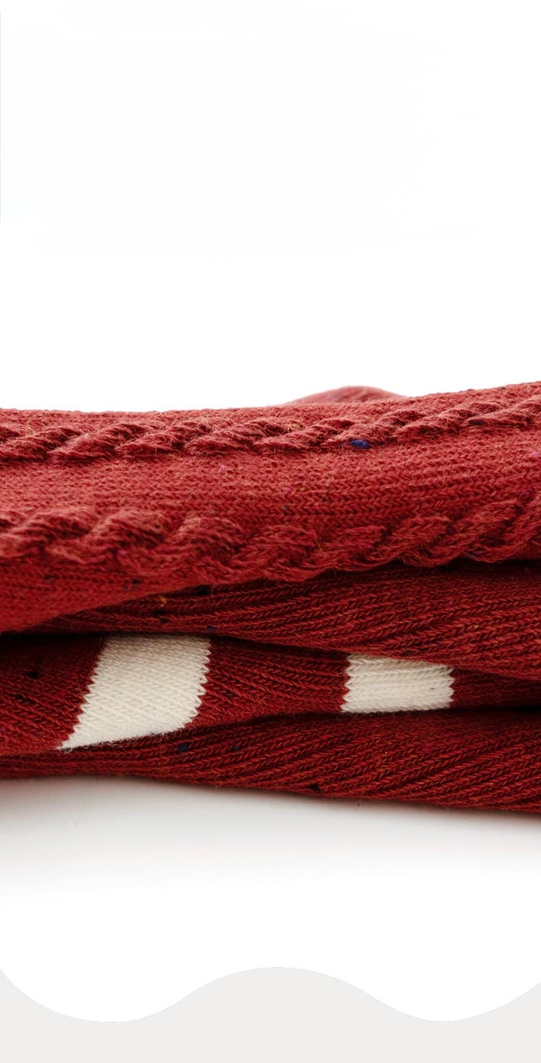 Close-up of folded red baby socks showing knit cotton texture and festive stripe detail.
