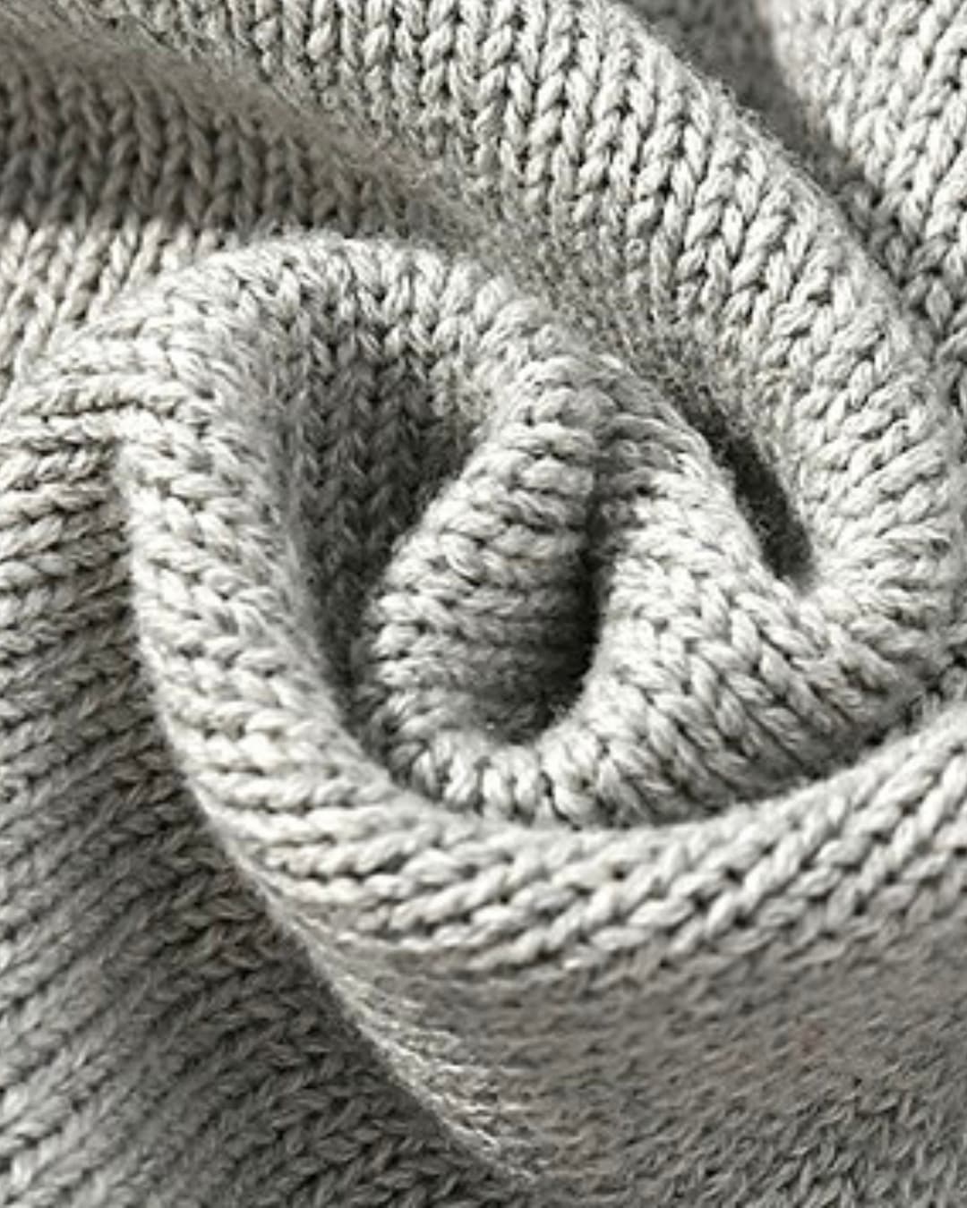 Close-up of gray cable knit fabric texture, showcasing thick soft cotton weave for baby romper.