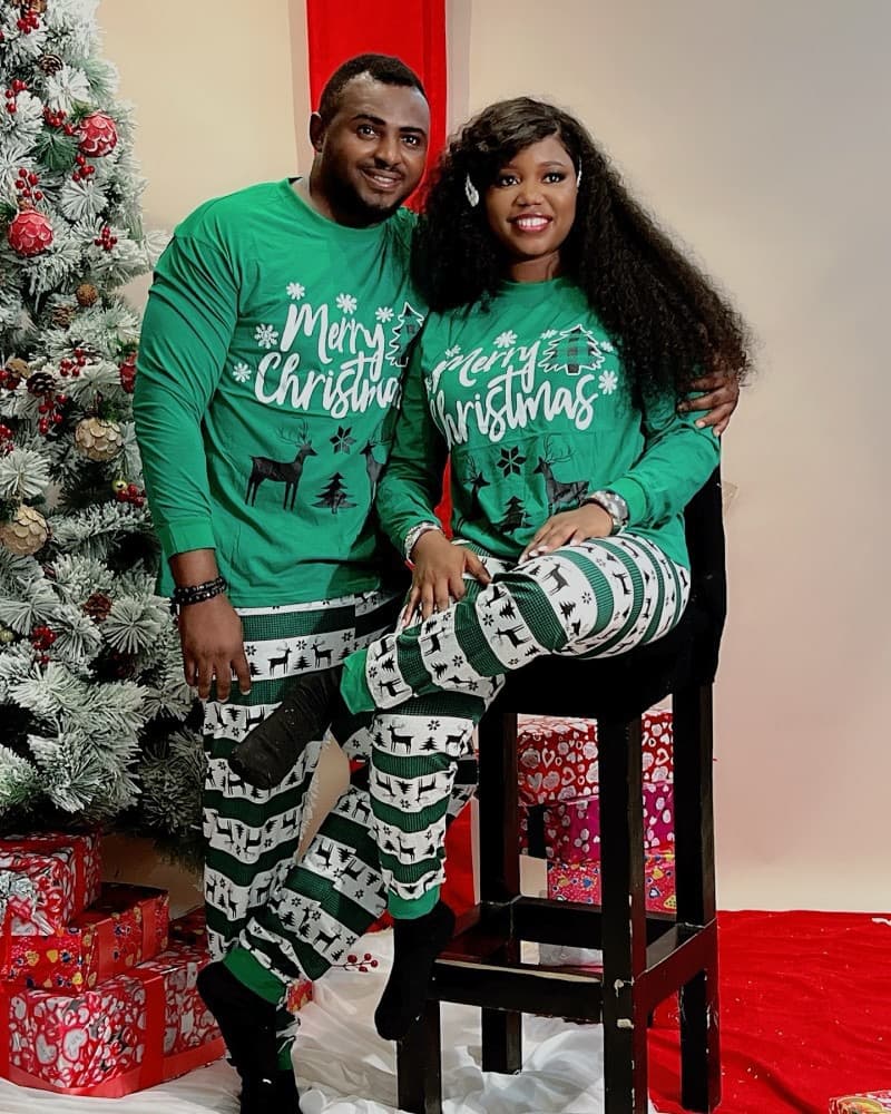 Couple wearing matching green Christmas pajamas with Merry Christmas text and reindeer print