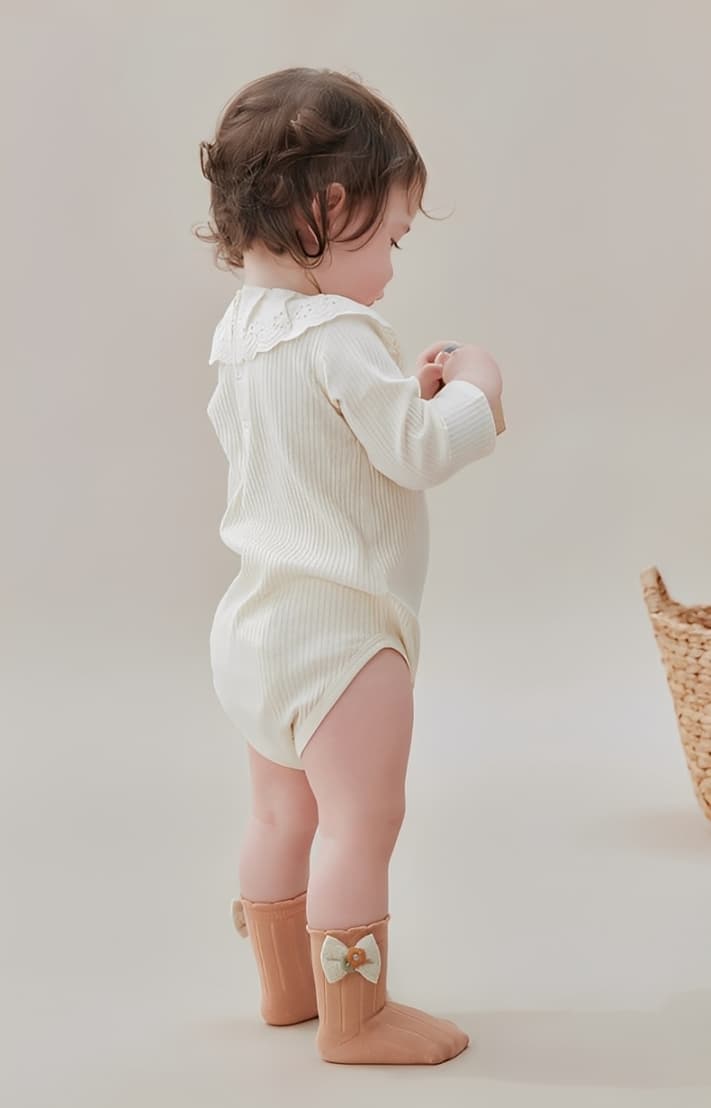 Side view of baby girl wearing soft cotton bow socks in pastel color.
