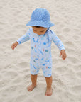 toddler wearing blue ocean whale rash guard swimsuit standing on sand beach UV swimwear
