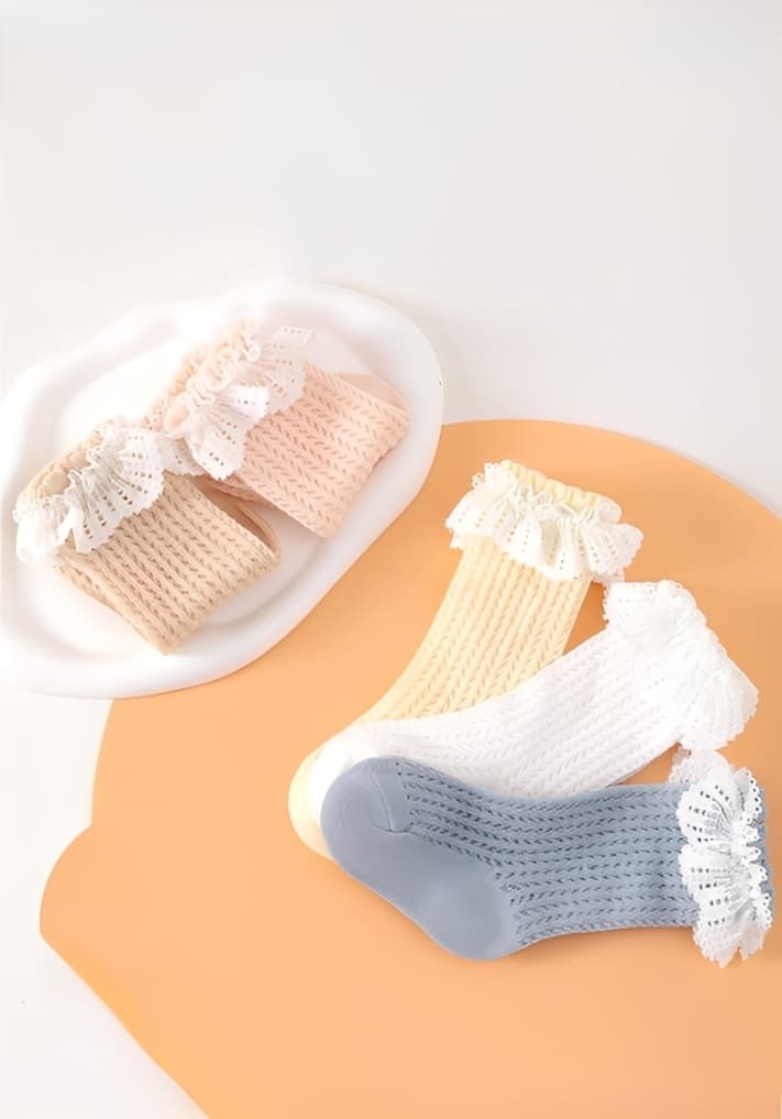 Set of pastel lace frill cotton baby socks in beige, yellow, white, and blue.