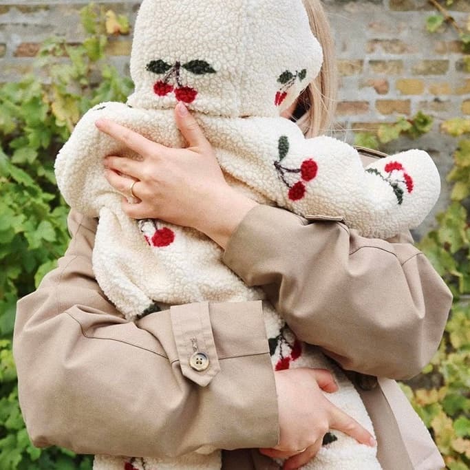 Mother holding baby wearing cherry-pattern fleece hooded jumpsuit for cozy outdoor warmth
