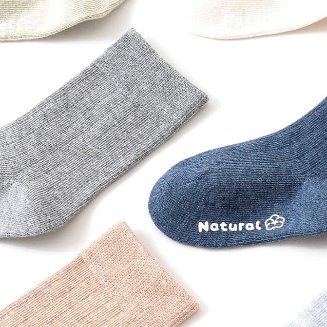 Flat lay of multi-color cotton socks for kids in blue, gray, beige, and pink — soft breathable material.