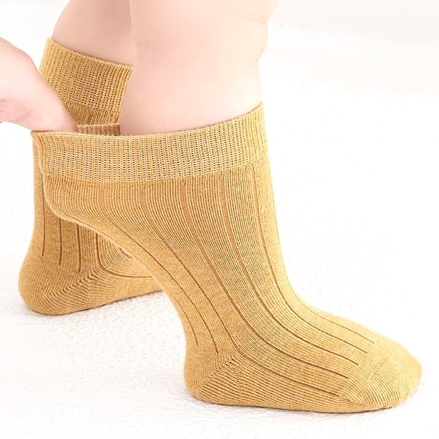 Mustard yellow cotton socks worn by child showing ribbed knit design and flexible fit.
