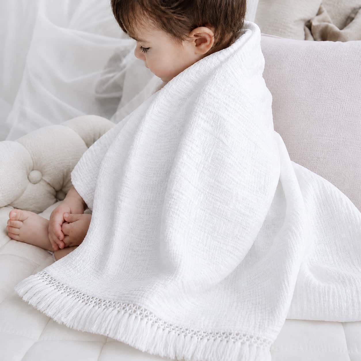 Newborn baby wrapped in a snow white cotton baby blanket, soft breathable nursery blanket for naps, swaddling and everyday comfort.