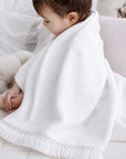 Newborn baby wrapped in a snow white cotton baby blanket, soft breathable nursery blanket for naps, swaddling and everyday comfort.