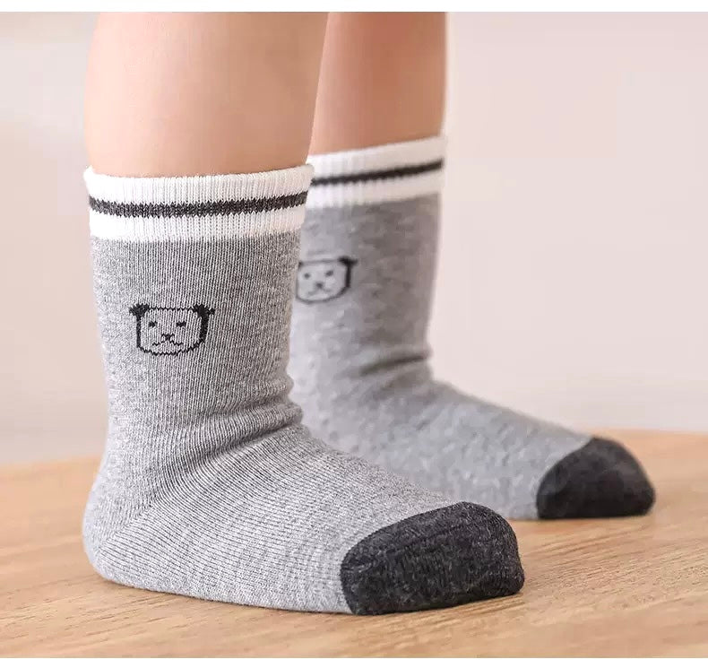 Lifestyle display of patterned cotton baby socks – grey, cream and yellow mix
