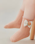 Peach cotton baby socks featuring a cute knitted bow and soft ribbed design.
