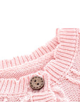 Neckline and button detail of pink embroidered knit baby romper showing fine stitching.
