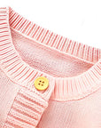 Close-up of wooden button neckline detail on pink knitted baby romper