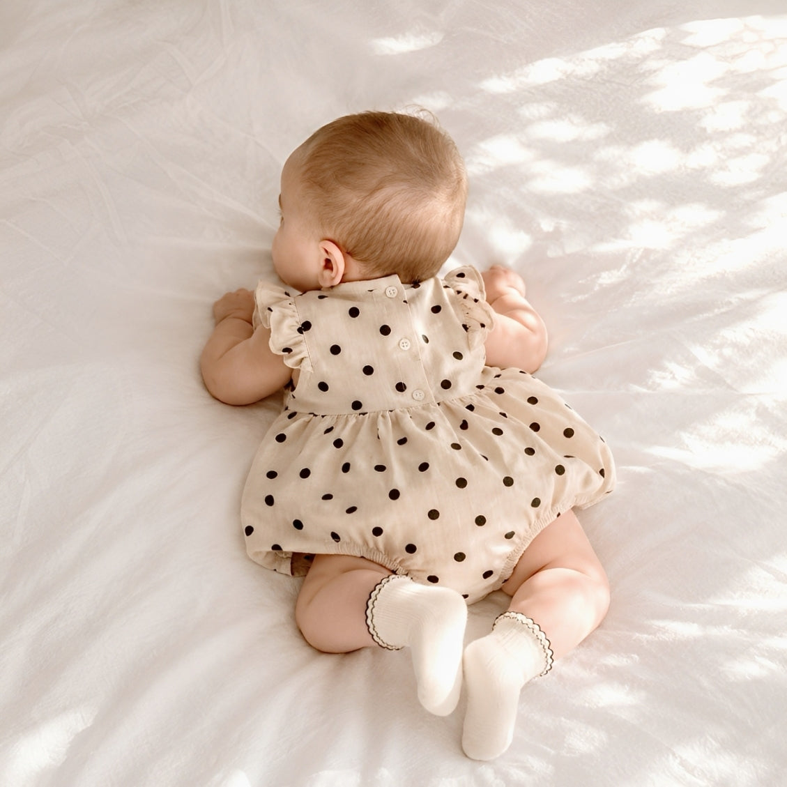 Baby wearing polka dot bubble romper with white scallop trim ribbed baby socks