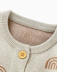 Close-up detail of collar and button on rainbow knit baby romper showing fine stitching and soft knitted fabric.
