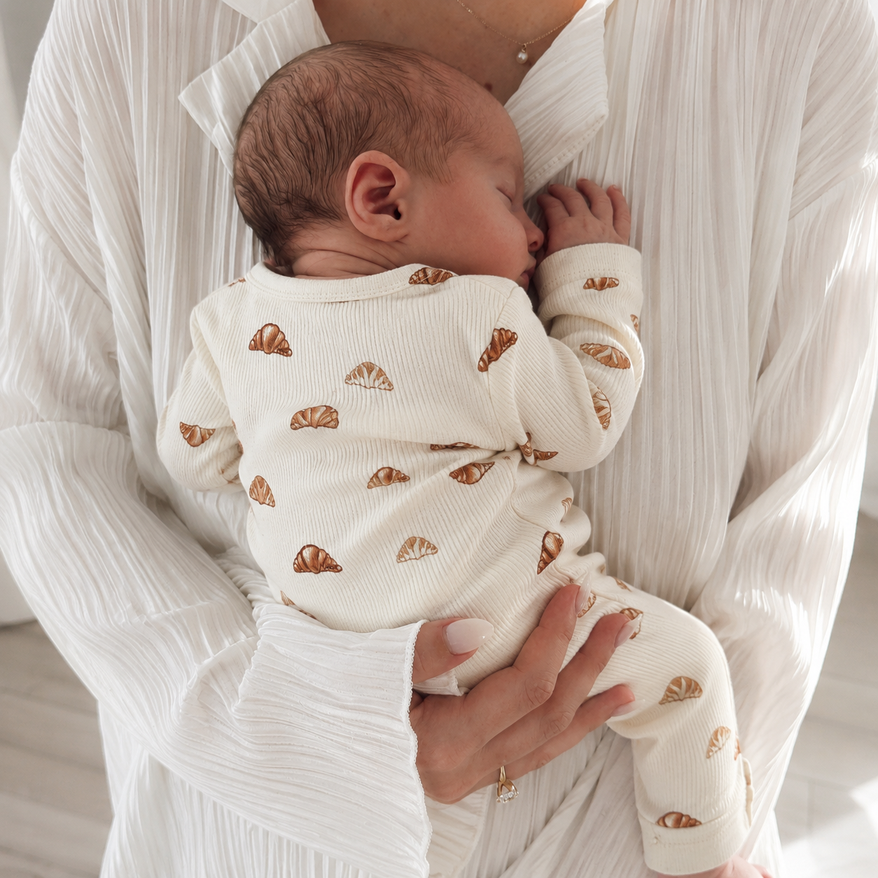 Newborn baby wearing a soft ribbed baby sleepsuit in minimalist neutral style for cosy everyday comfort