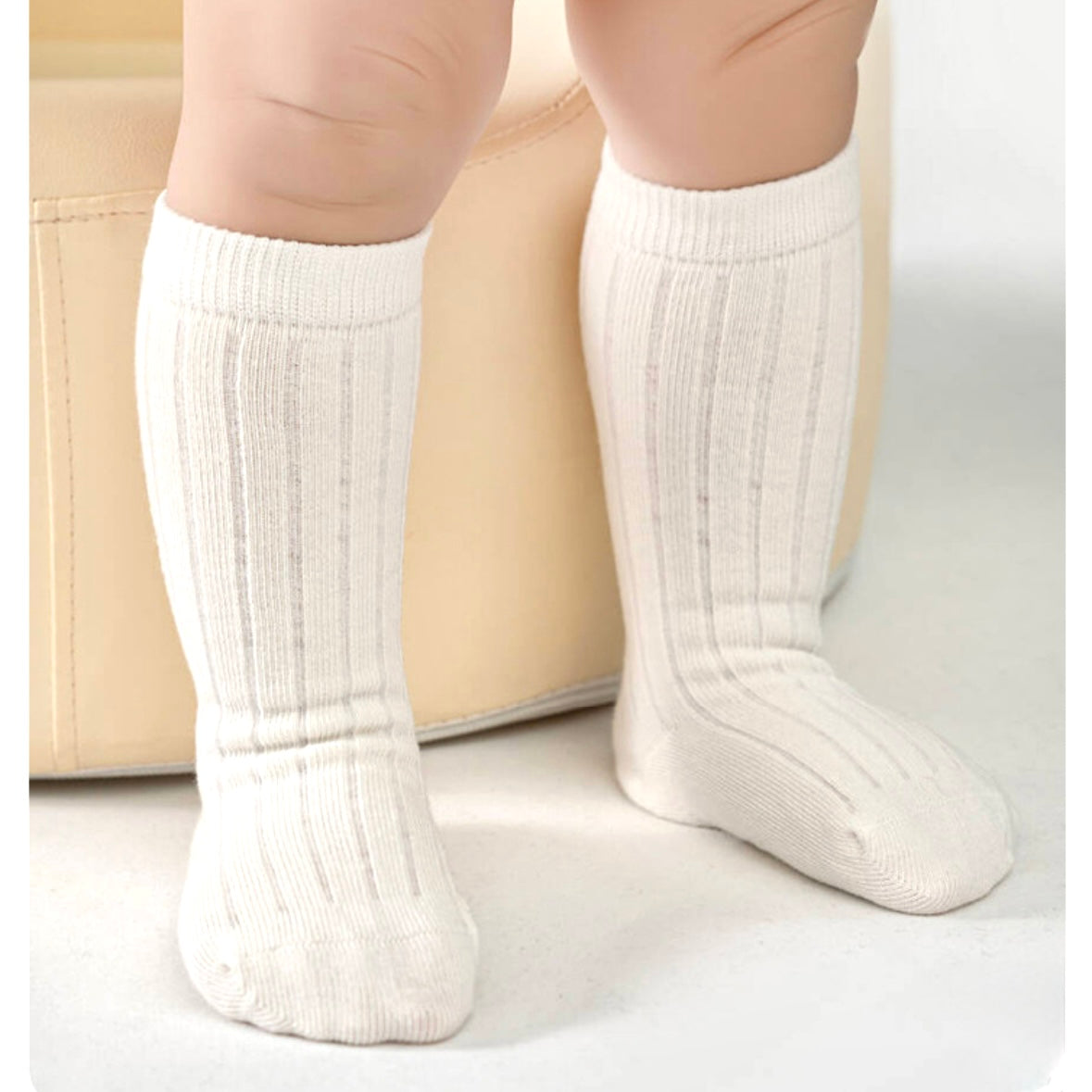 White knee-high socks worn by a child on a light background