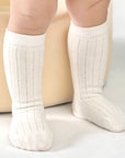 White knee-high socks worn by a child on a light background