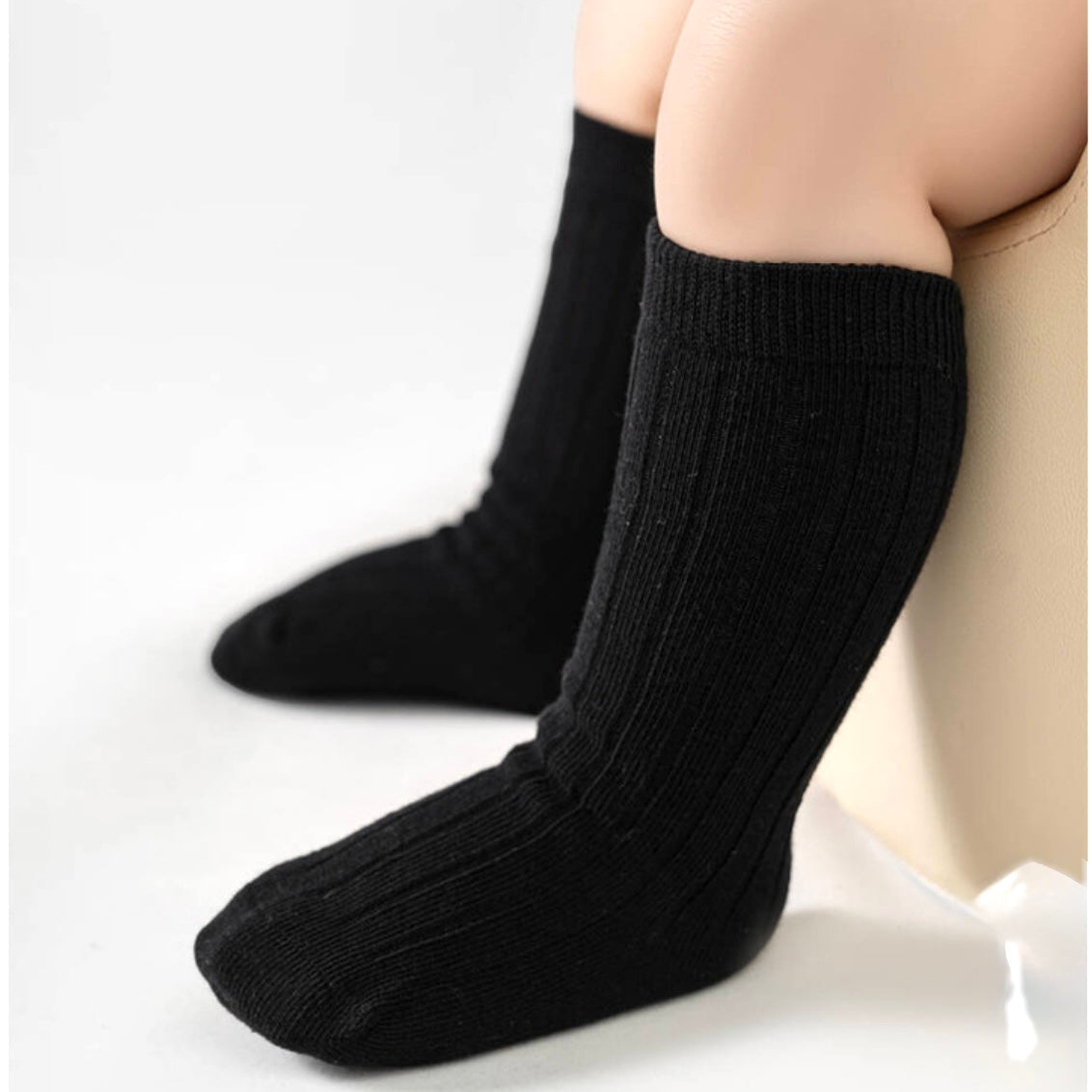 Black socks worn by a baby on a white background