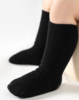 Black socks worn by a baby on a white background